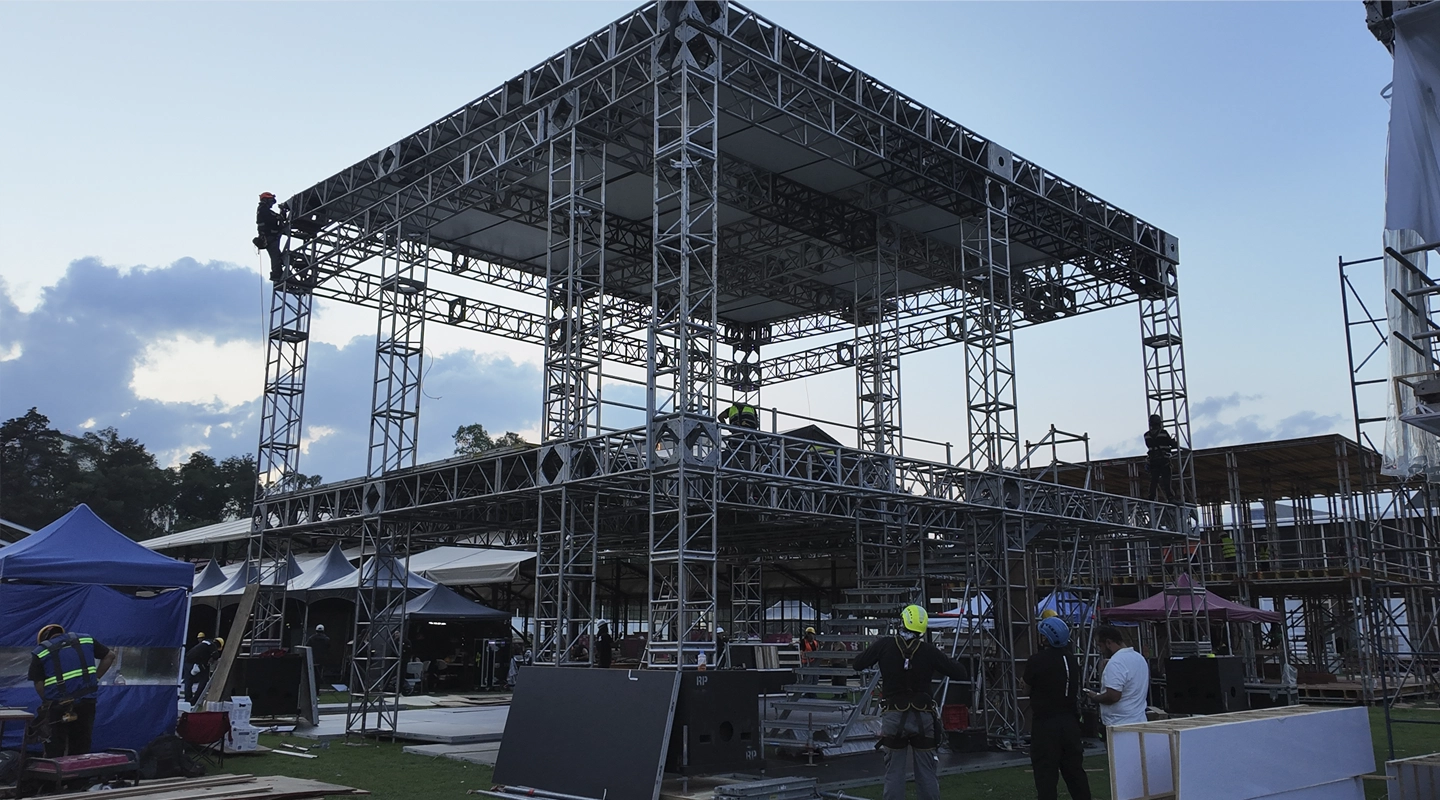 Estructura hospitality de dos niveles con truss MK de aluminio, escaleras layher, diseñada para soportar plataformas, cubiertas y cargas de uso en instalaciones temporales para eventos